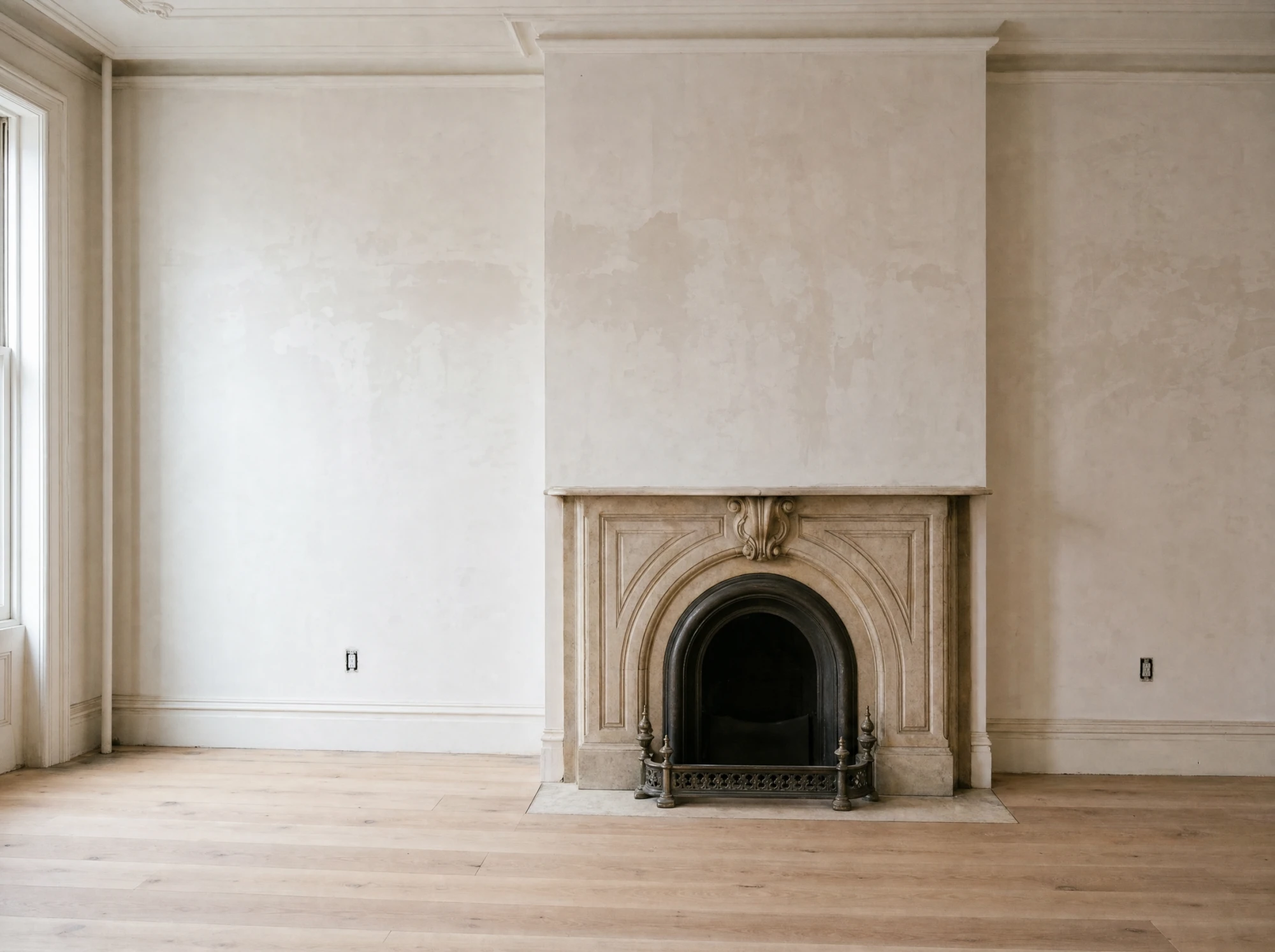 Restored parlor floor with the original marble mantel and tall windows, plaster freshly patched