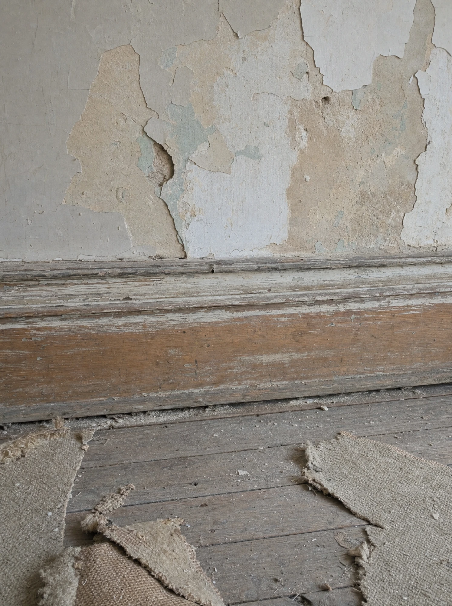 Original baseboard and peeling plaster, kept as found during the rebuild