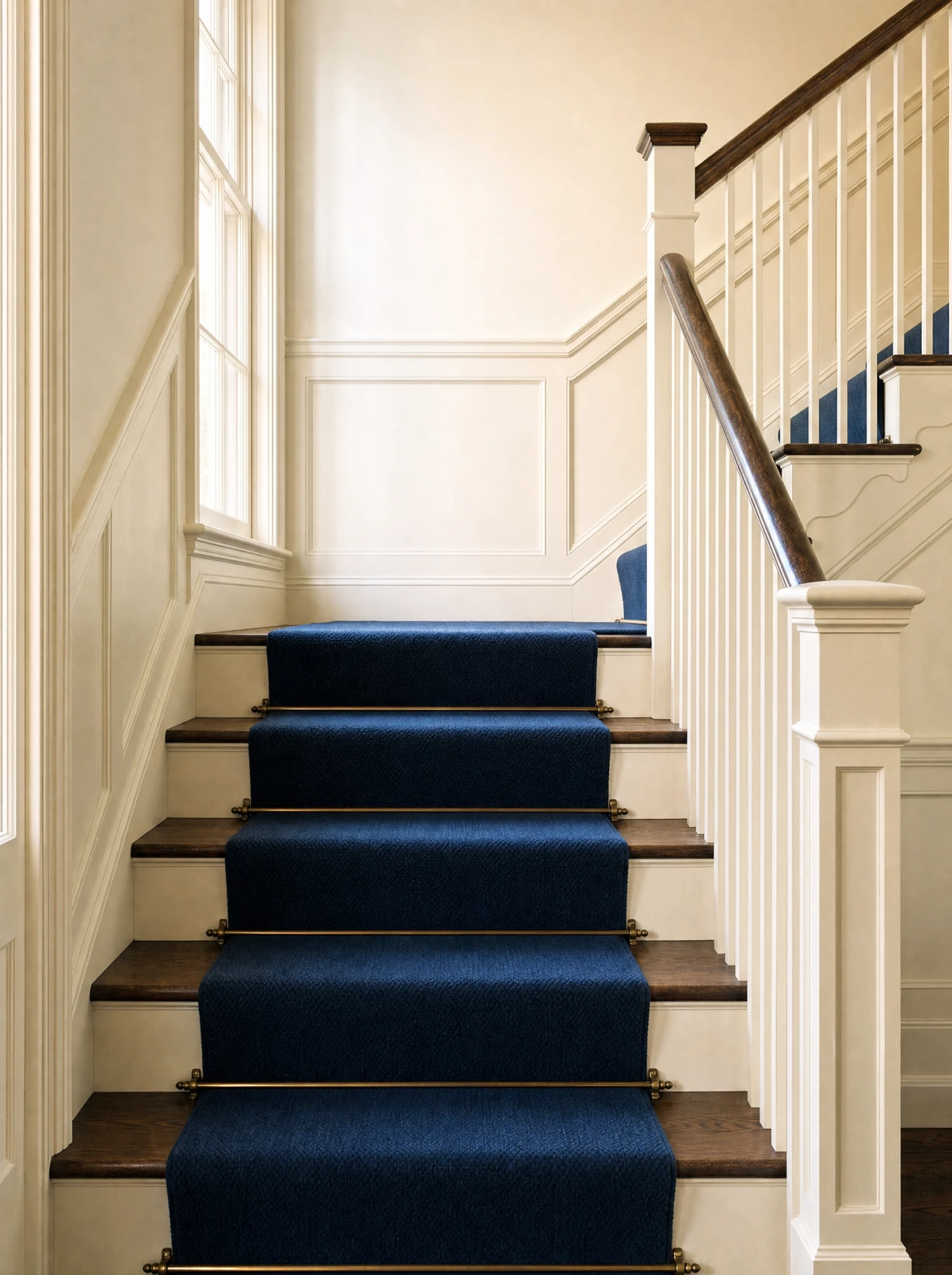 Navy stair runner rising past white-painted panelling
