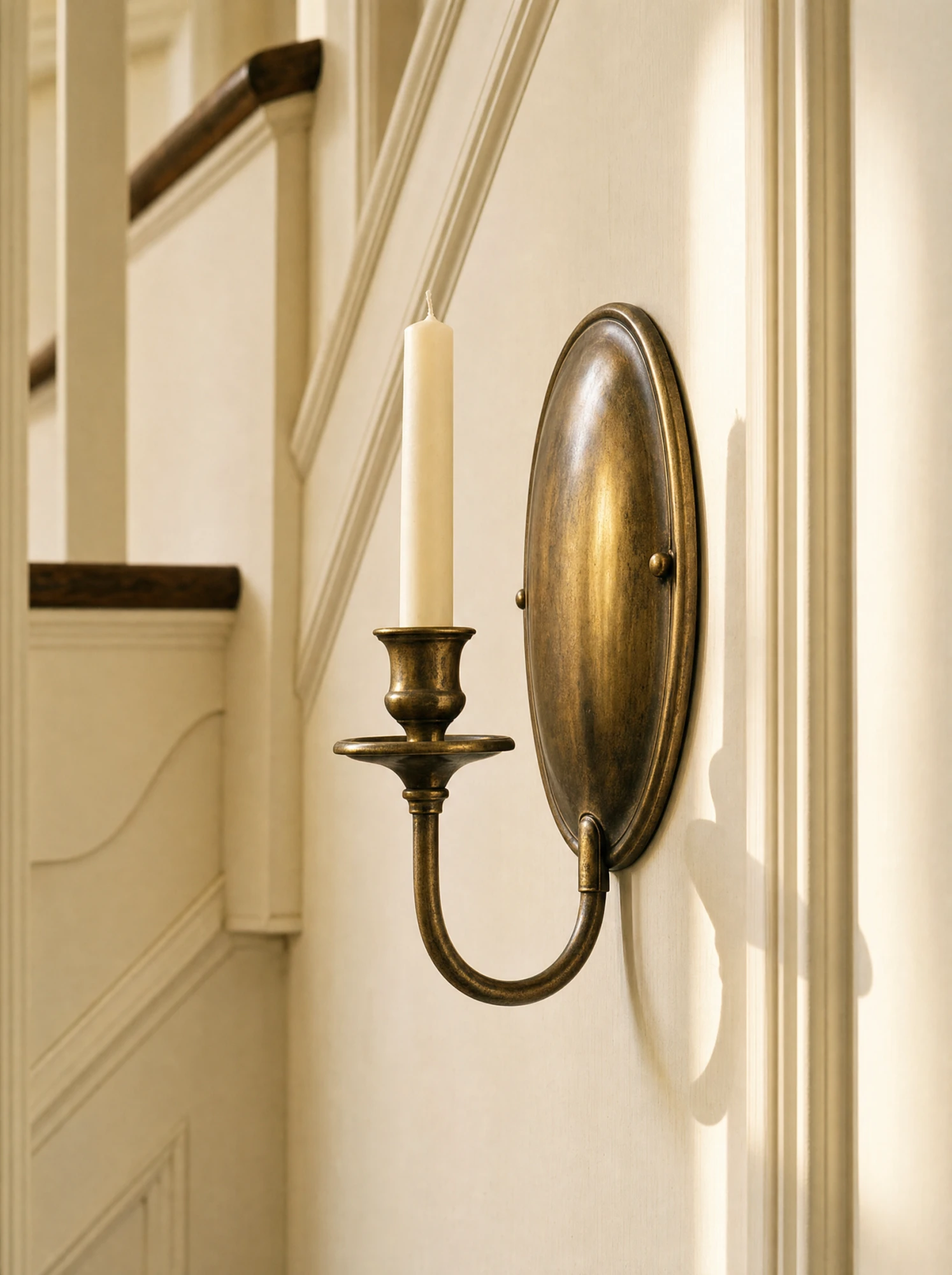Aged-brass candle sconce on the stair wall